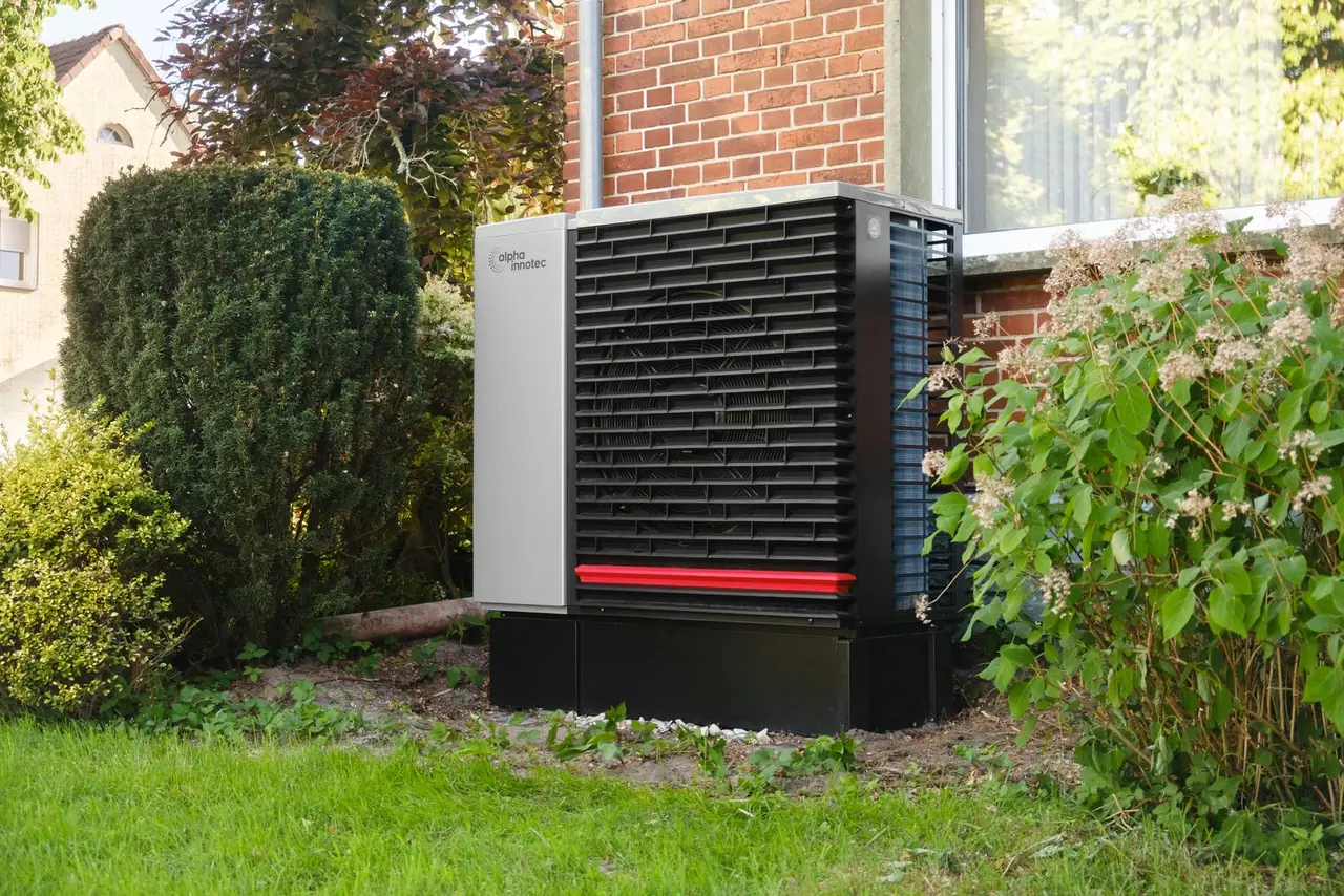 A residential heat pump installed beside a brick house