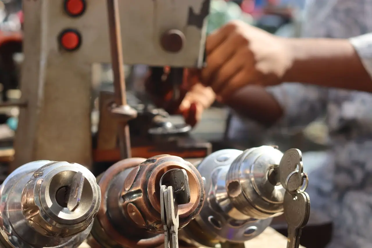 A locksmith cutting a key on a key-cutting machine, lock cylinders in the foreground