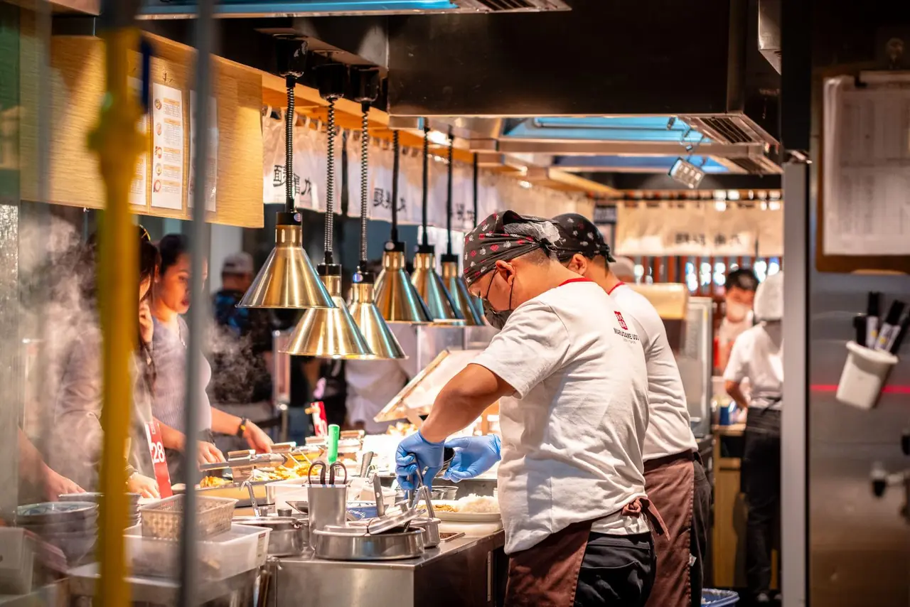 Chefs preparing food in a vibrant Asian restaurant kitchen, Metro Manila.