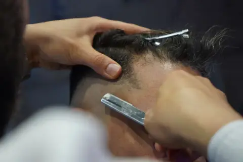 A barber shaving a client with a straight razor