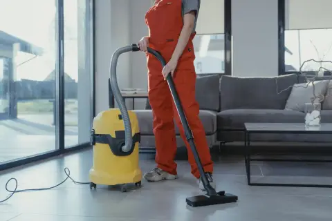 A professional cleaner vacuuming a living room