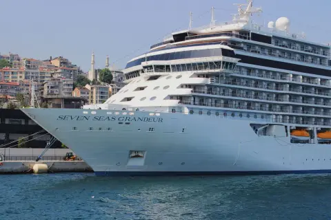 A majestic cruise ship moored in the scenic harbor of Istanbul with cityscape in the background.