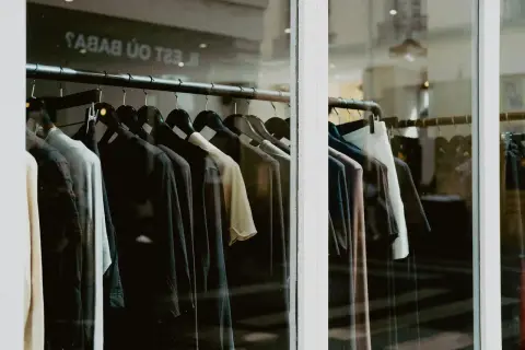 Close-up of clothing on hangers inside a fashion store window.