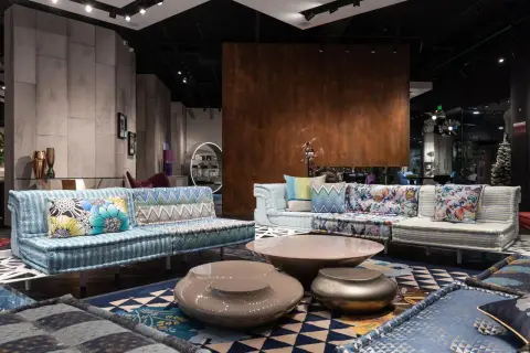 Comfortable sofas with colorful cushions and creative coffee tables placed on carpet in modern spacious furnit
