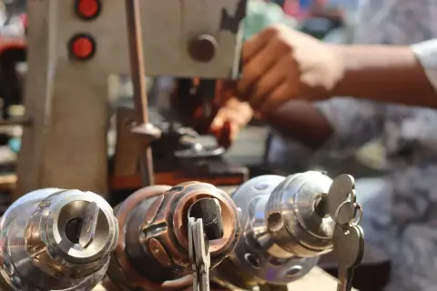 A locksmith cutting a key on a key-cutting machine, lock cylinders in the foreground