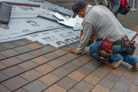 A roofer installing asphalt shingles on a residential roof