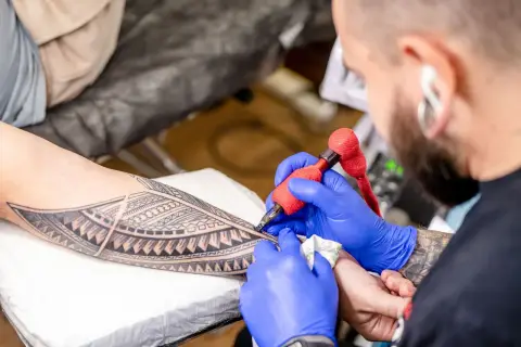A tattoo artist applying an intricate design to a client's arm