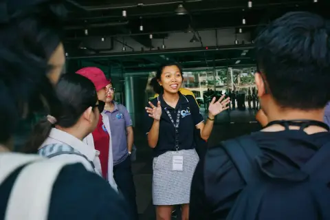 Tour guide leading a group tour, engaging visitors with gestures in an outdoor urban setting.