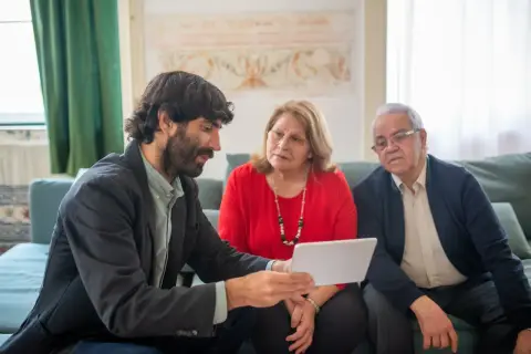 A financial advisor discussing investment options with an elderly couple in a cozy living room.
