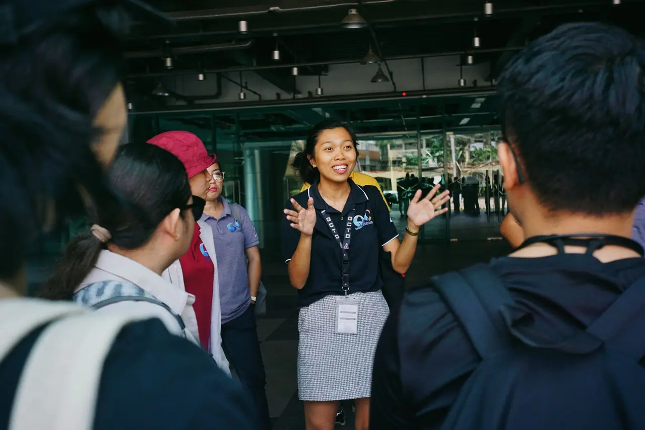 Tour guide leading a group tour, engaging visitors with gestures in an outdoor urban setting.